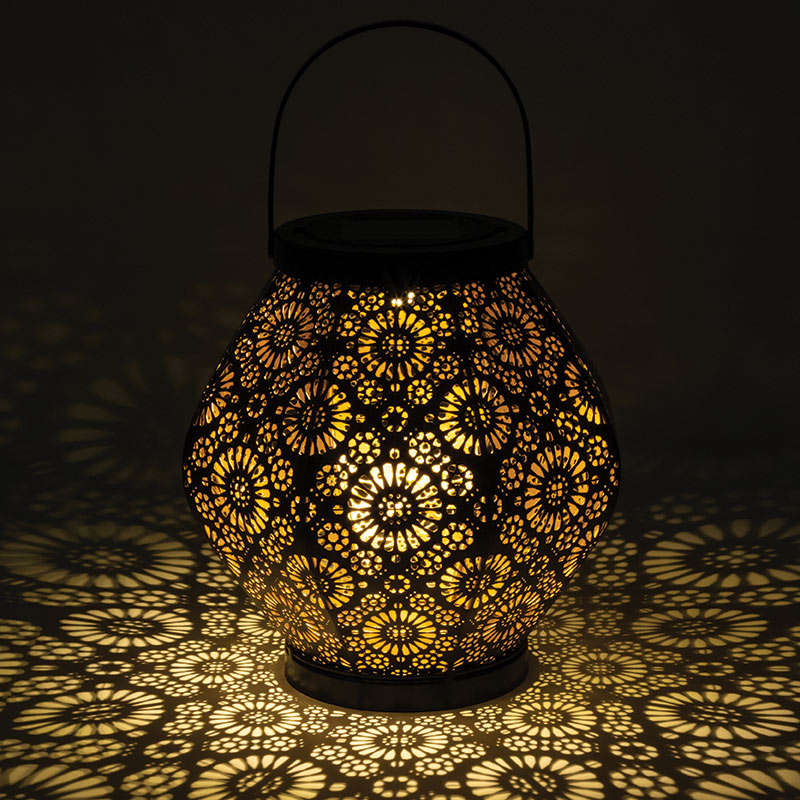 Solar Floral Lantern lit in a dark room and casting floral shadows