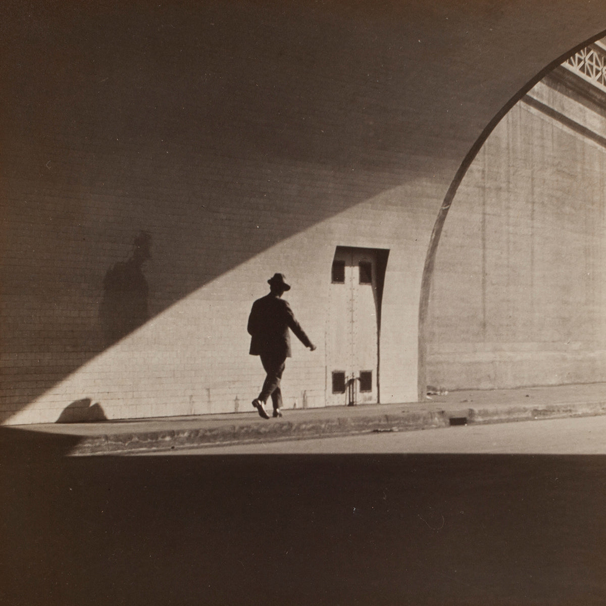 photo of man walking through tunnel