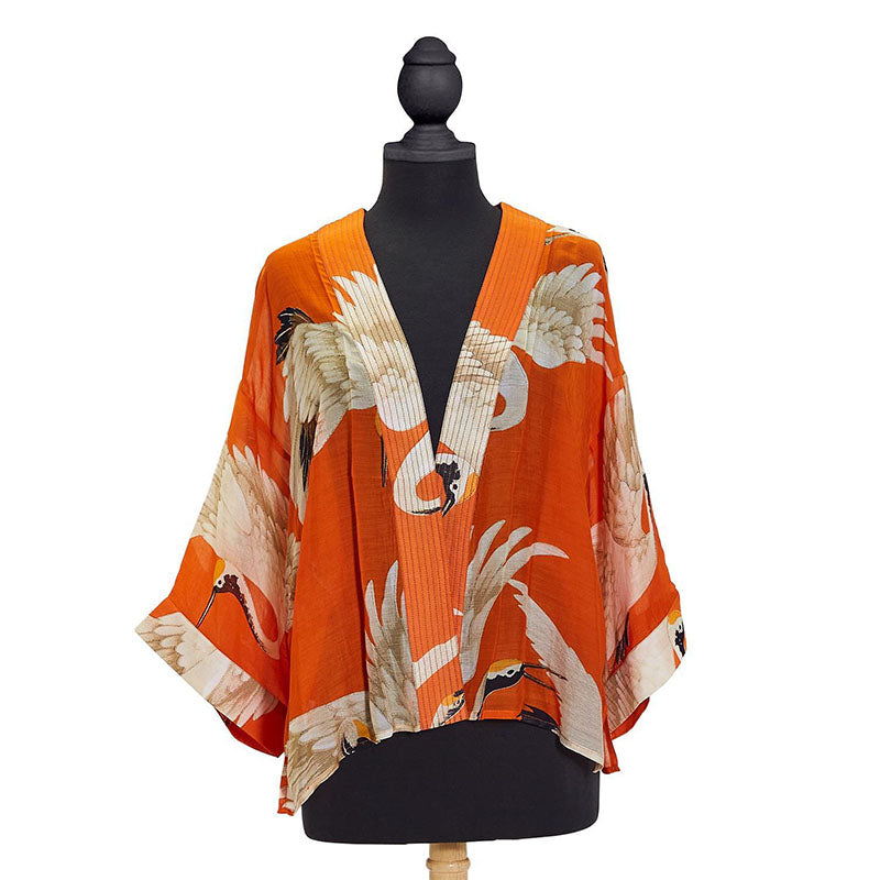 Short kimono style orange jacket with images of white cranes on mannequin